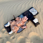 baby lying on waterproof change mat at the beach using a compact bag